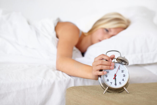 alarm-clock-woman-wake-up-morning-bed-home-with-fatigue-rest-press-snooze-girl-frustrated-with-time-tired-start-day-bedroom-routine-apartment-with-timer