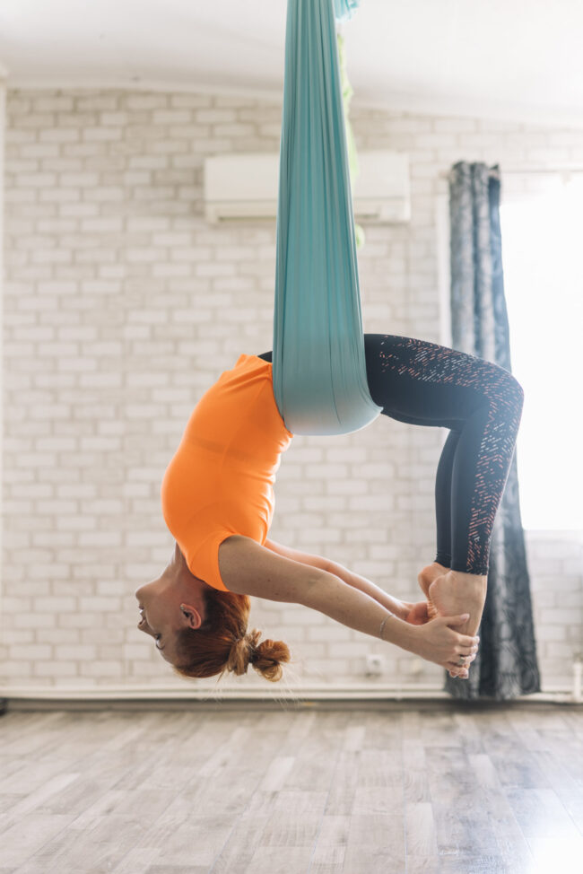 beautiful-young-woman-hanging-upside-down-while-practicing-aerial-yoga