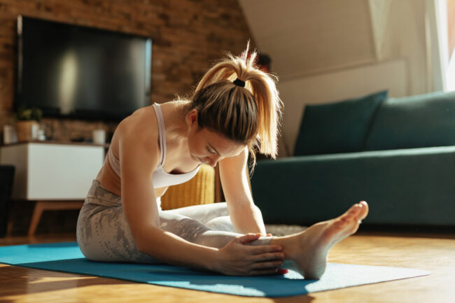 Young woman doing stretching exercises on the floor at home.